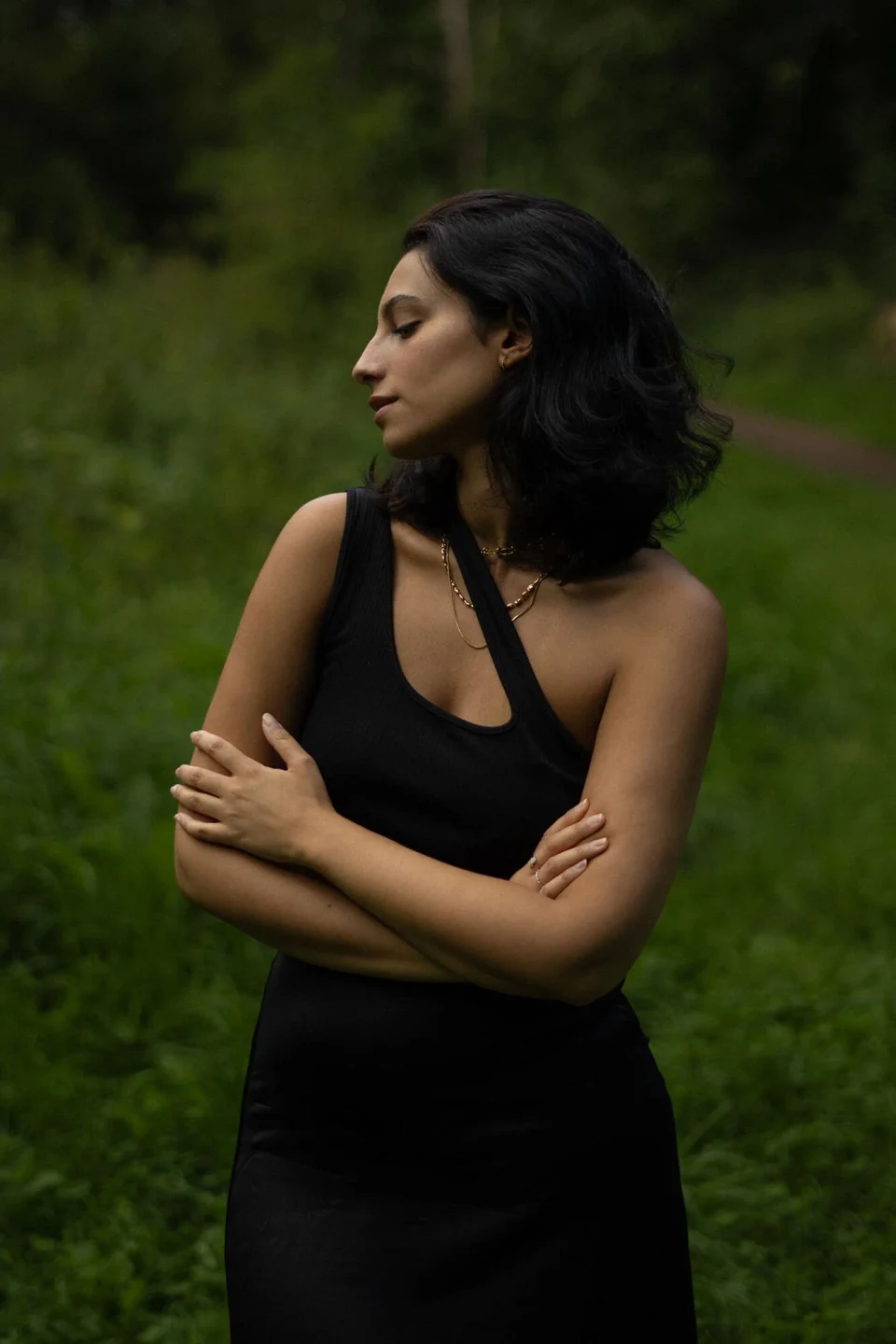 Woman in a forest crossing her arms and looking to the side