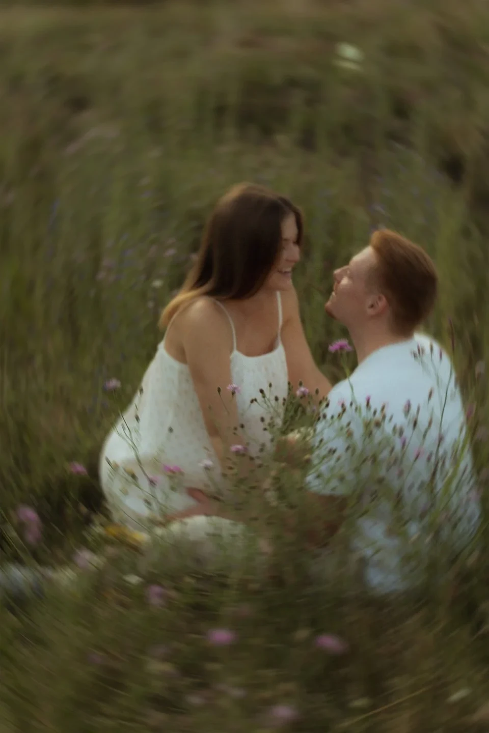 Couple sitting in a meadow and laughing together