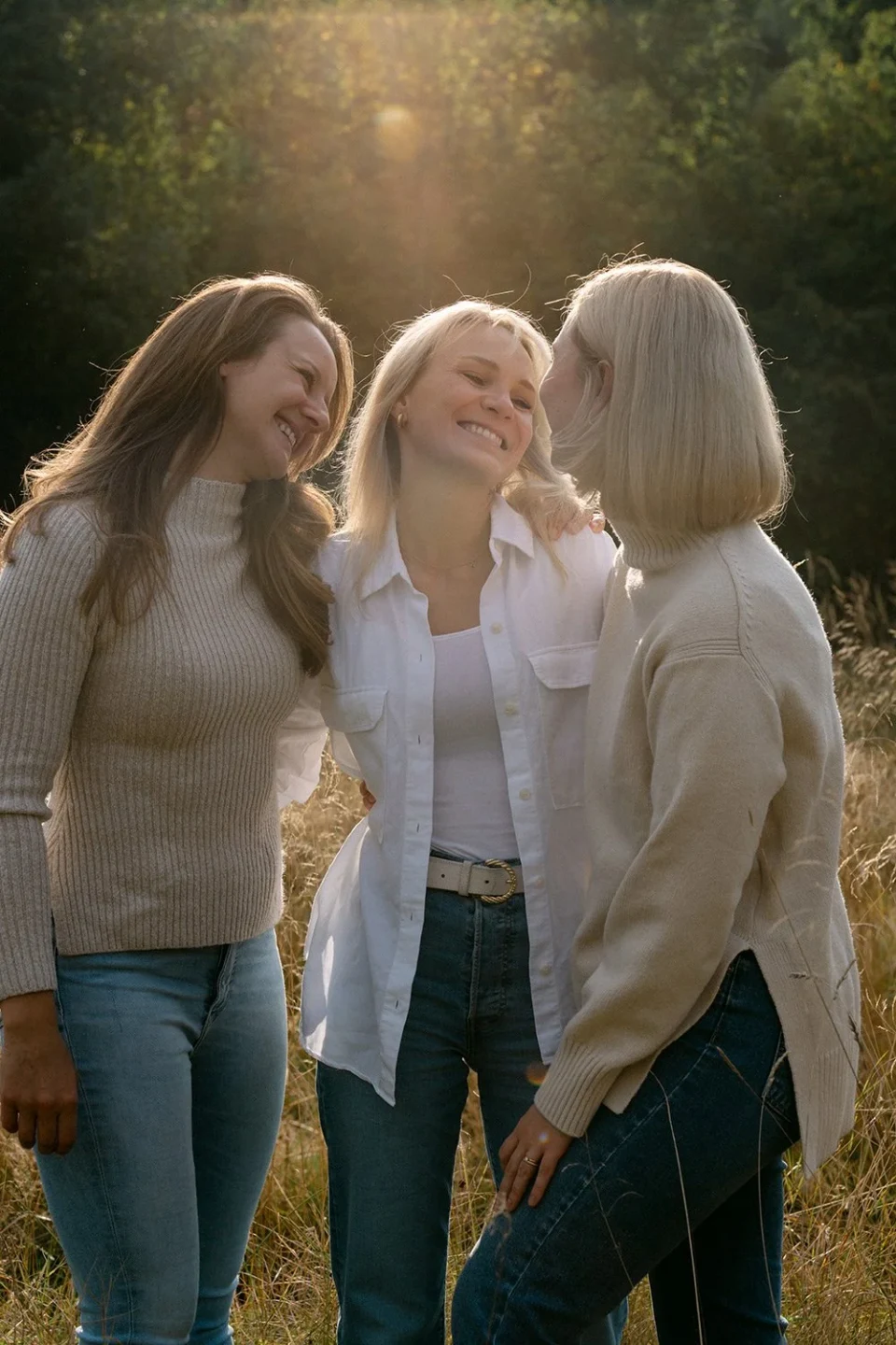 Three friends smiling at each other at sunset