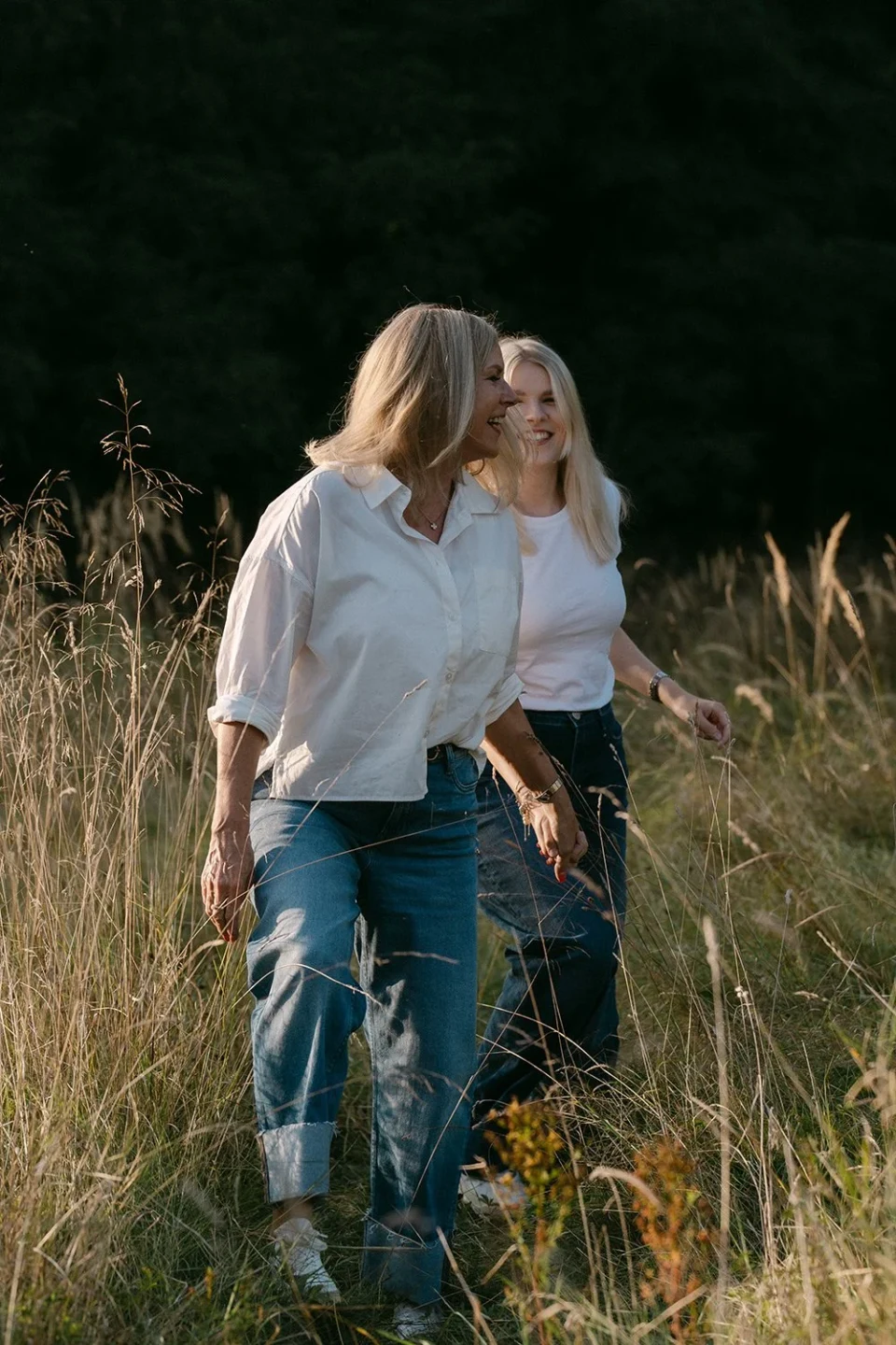 Mother and daughter walking through a meadow