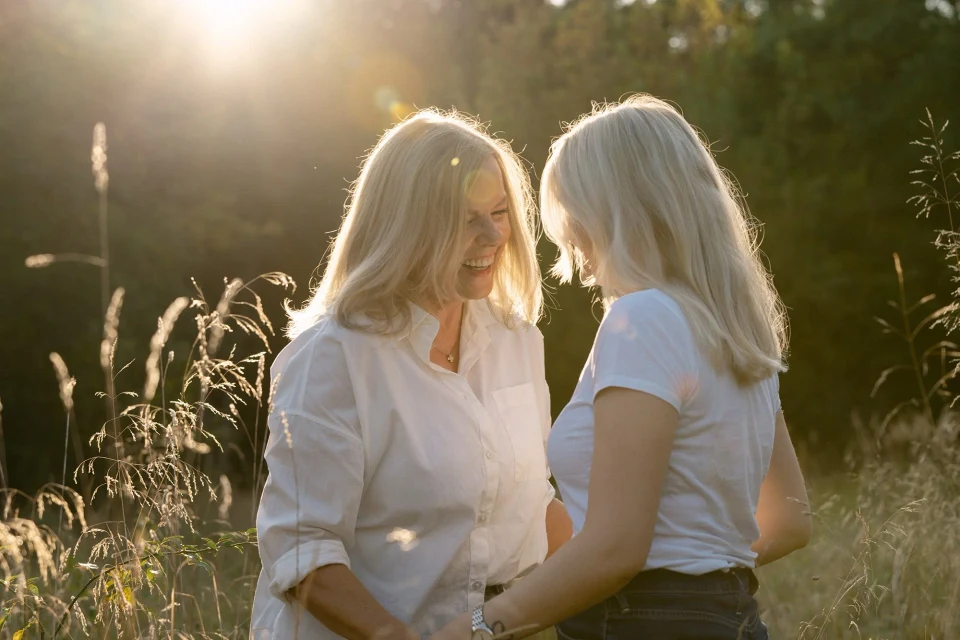 Mother and daughter holding hands and laughing at sunset