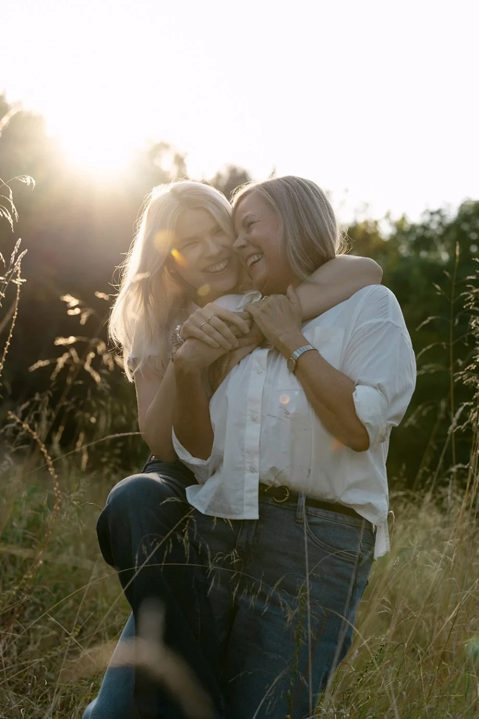 Daughter embracing her mother from behind as they laugh