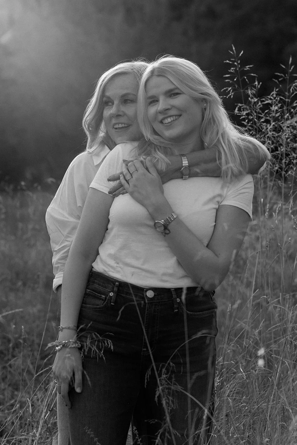 Mother embracing her daughter from behind as they laugh