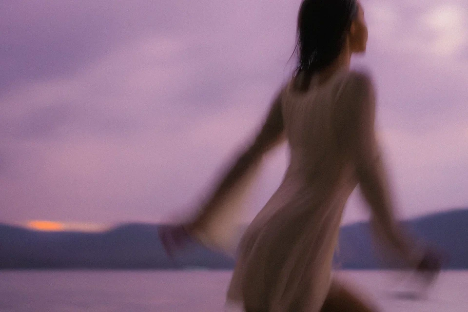 Woman running into the sunset, seen from behind