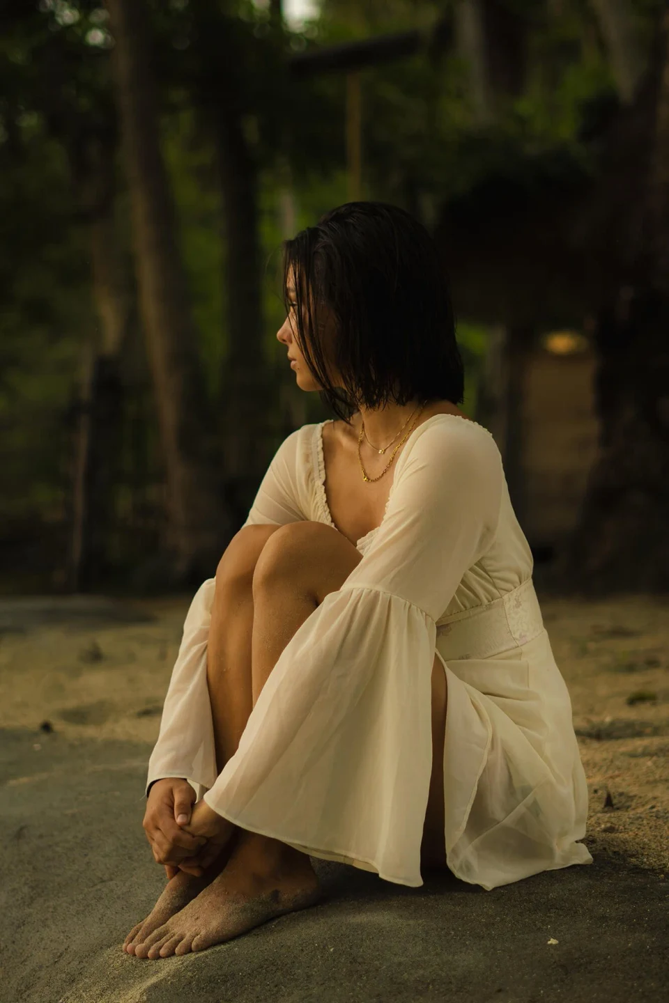 Woman in a white dress sitting on a rock with her knees drawn up