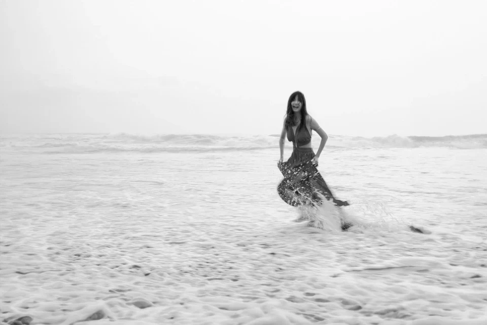 Woman in a dress running through shallow water on a beach