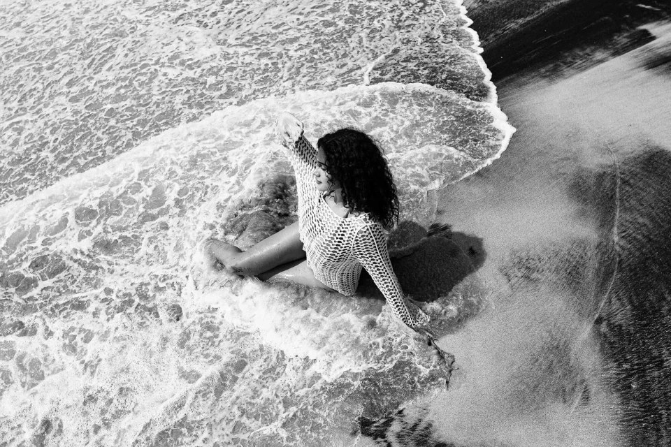 Woman sitting in the waves and looking into the distance