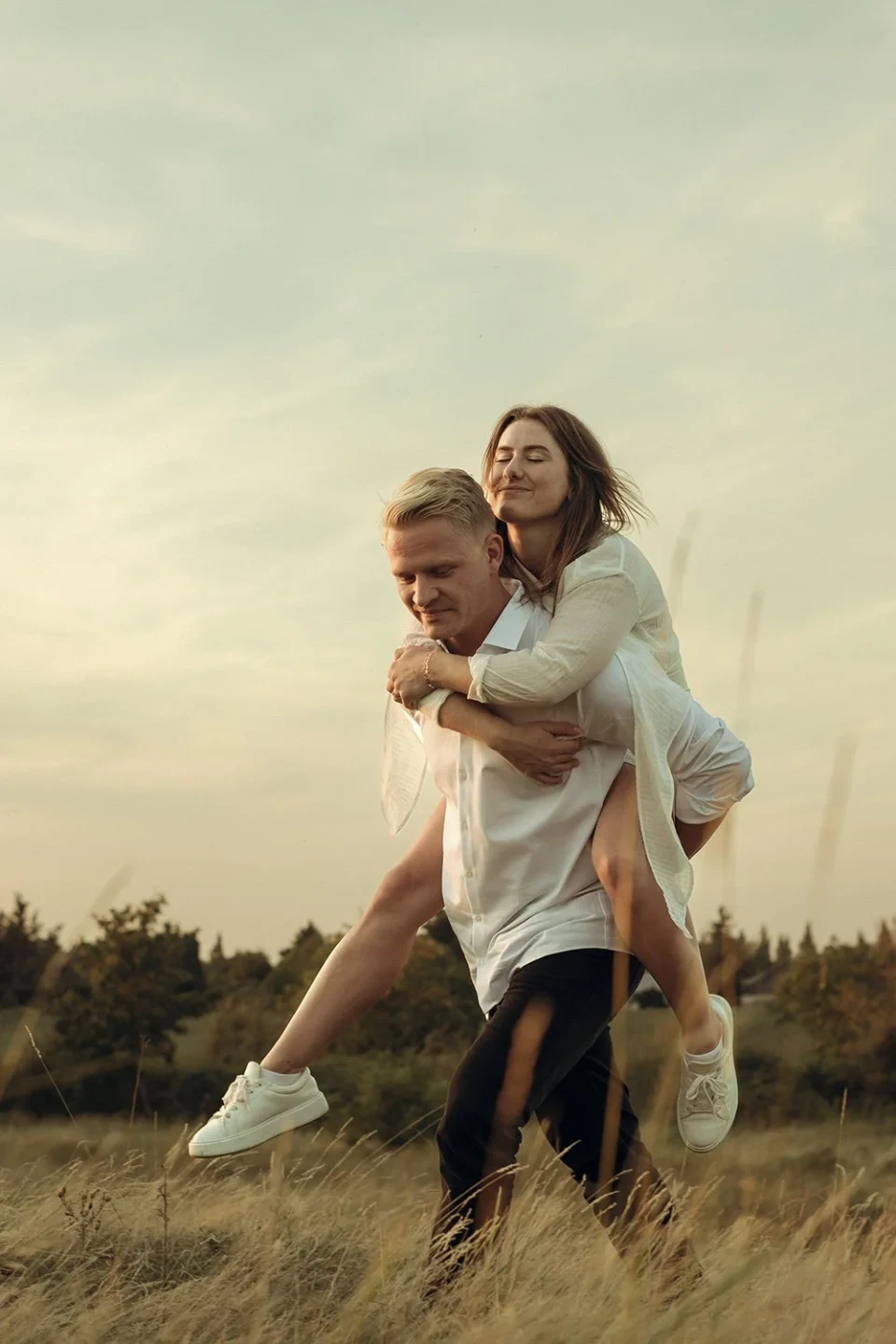 Man carrying his girlfriend across a meadow