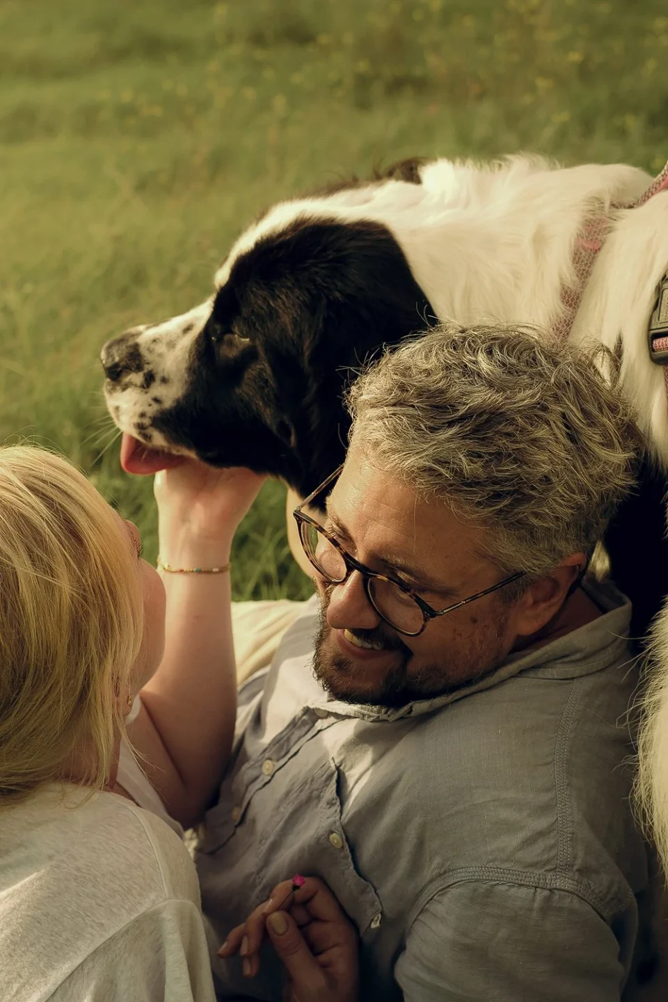 Couple and their dog sitting together in a meadow