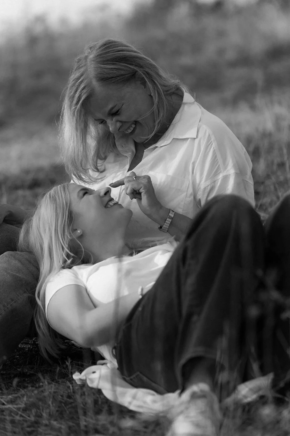 Mother and daughter sitting in a meadow and laughing
