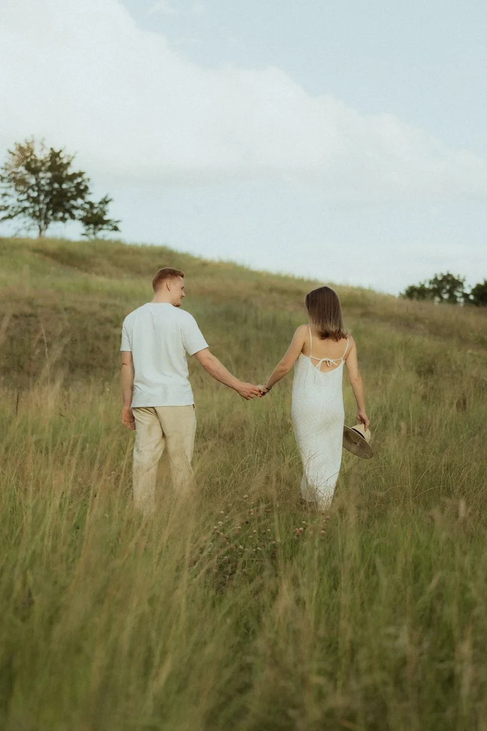 Couple walking through a meadow and looking at each other