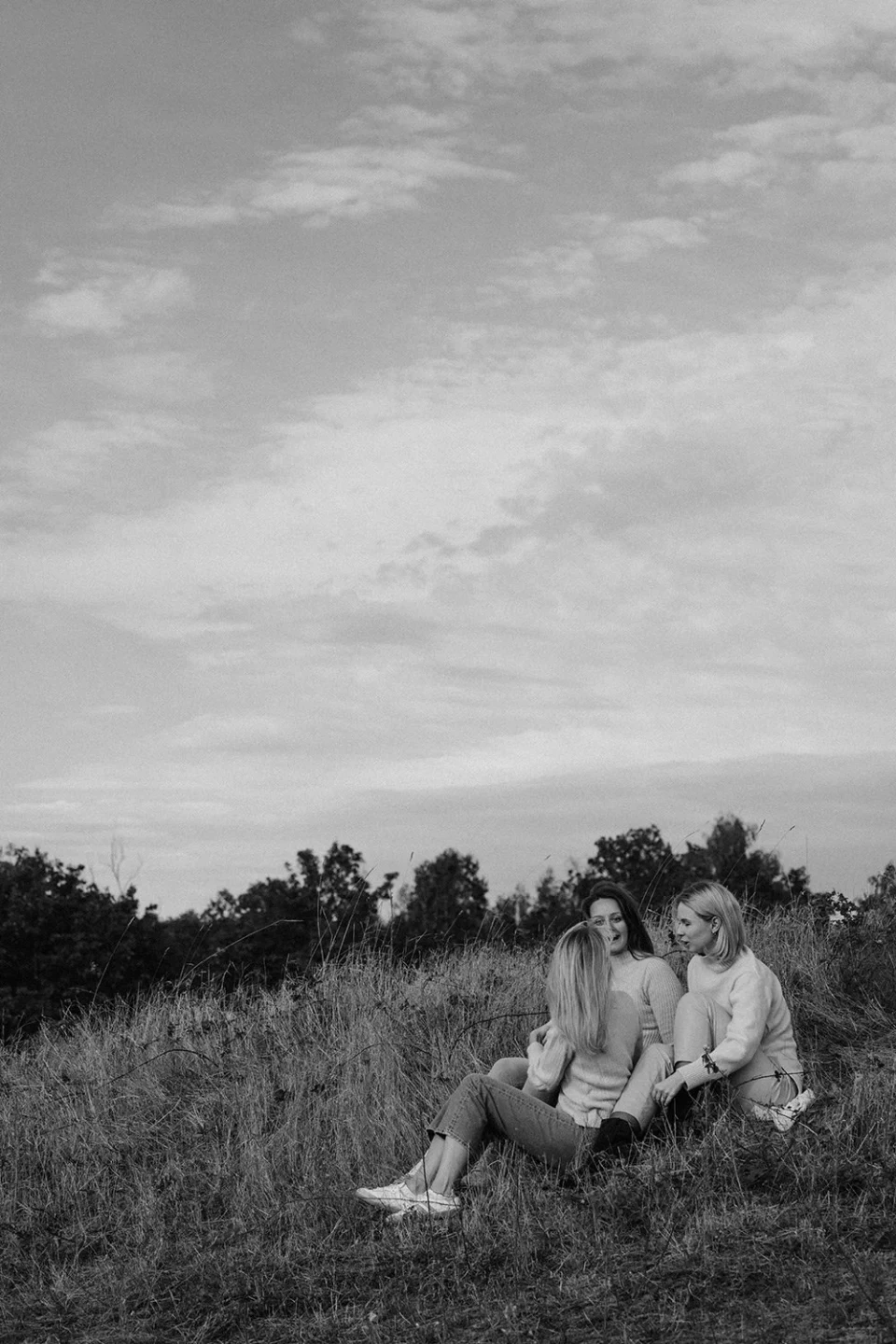 Three women sitting in a meadow and talking