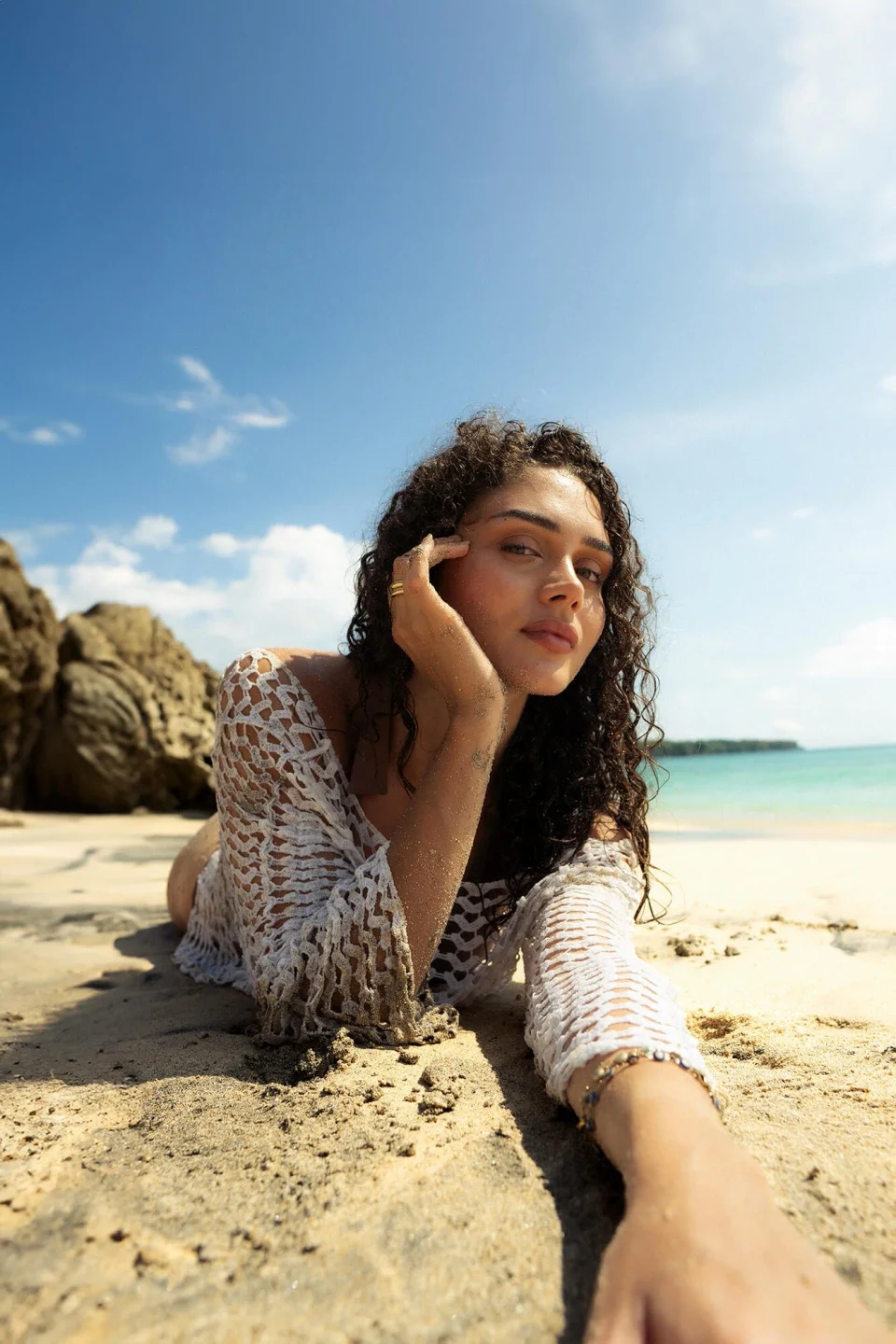 Woman lying on a beach with her head resting on her hand