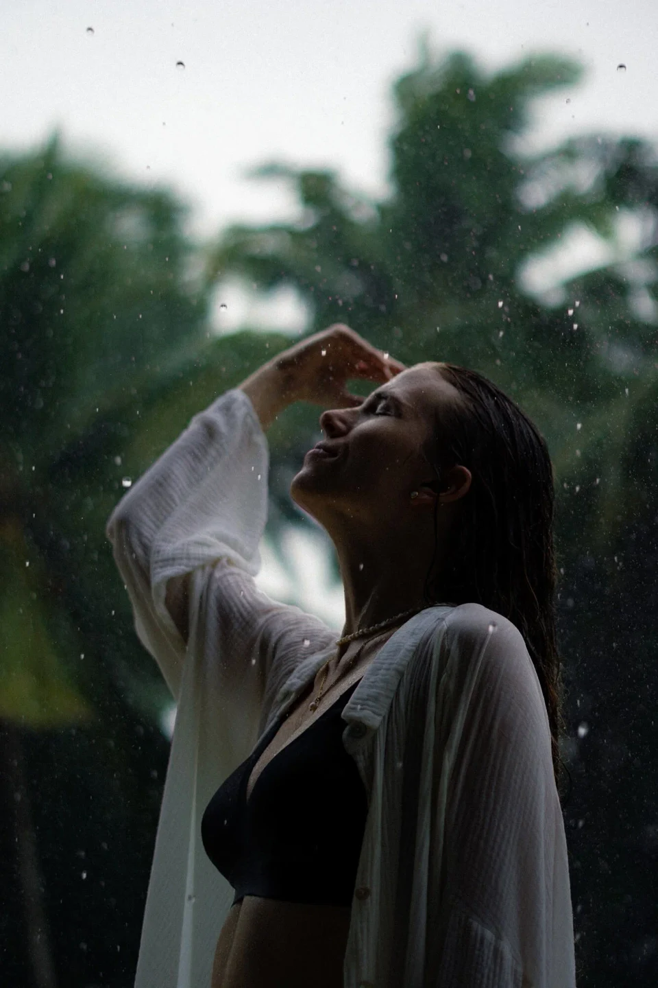 Woman standing in rain against a tropical backdrop