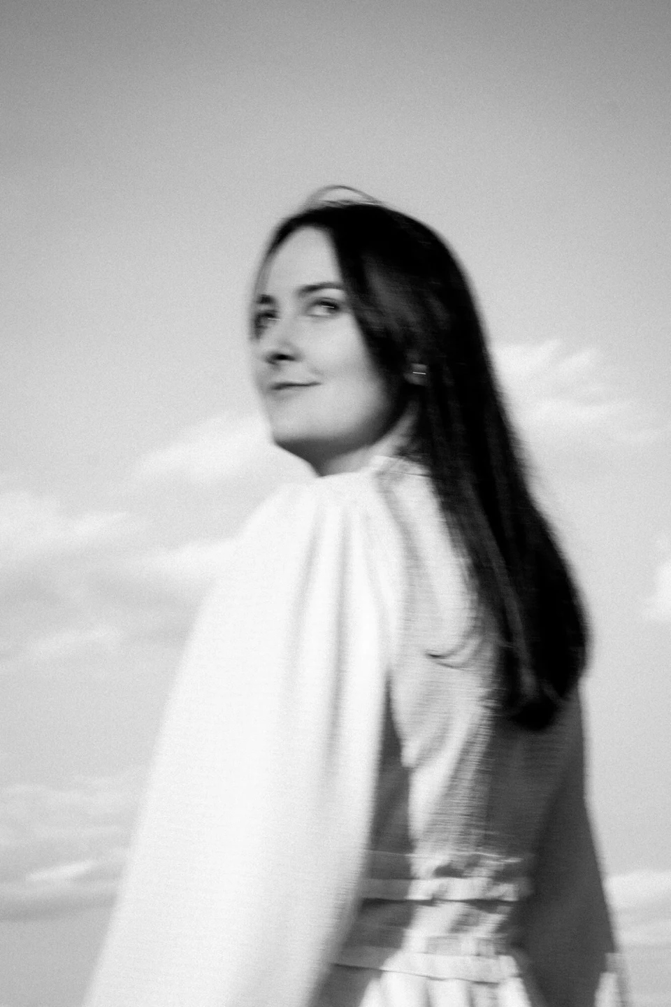 Woman looking over her shoulder against a blue sky